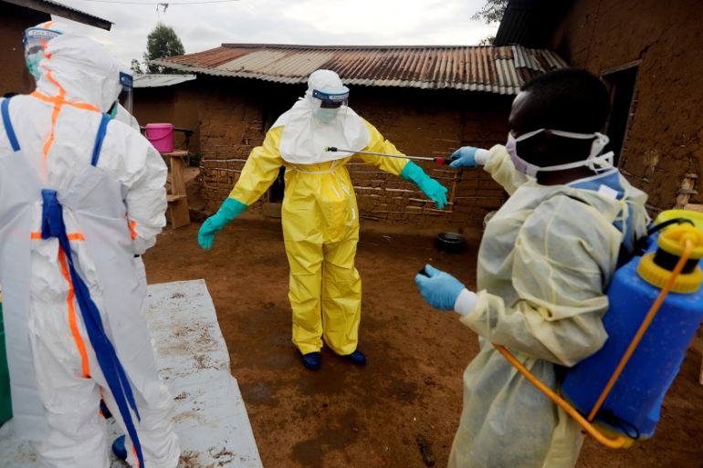 Kavota Mugisha Robert, a healthcare worker, who volunteered in the Ebola response, decontaminates his colleague after he entered the house of 85-year-old woman, suspected of dying of Ebola, in the eas