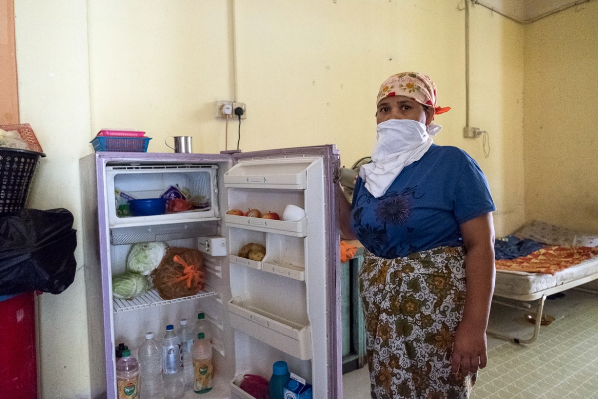 Nurjaan, 53 years old, covered her face with an improvised mask while posing for a portrait in her kitchen. Nurjaan''s daughter, Halayda, 24 years old, explains the financial difficulties they are faci