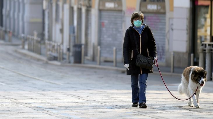 A woman wearing protective mask and gloves walks a dog, as the spread of coronavirus disease (COVID-19) continues, in Milan, Italy April 4, 2020. REUTERS/Daniele Mascolo