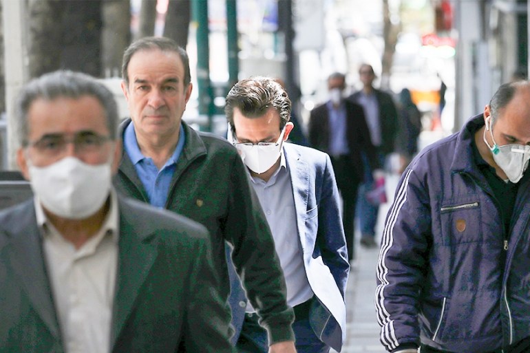 People wearing face masks to protect against the new coronavirus walk on a sidewalk in northern Tehran, Iran, Saturday, April 4, 2020. In the first working day after Iranian New Year holidays authorit