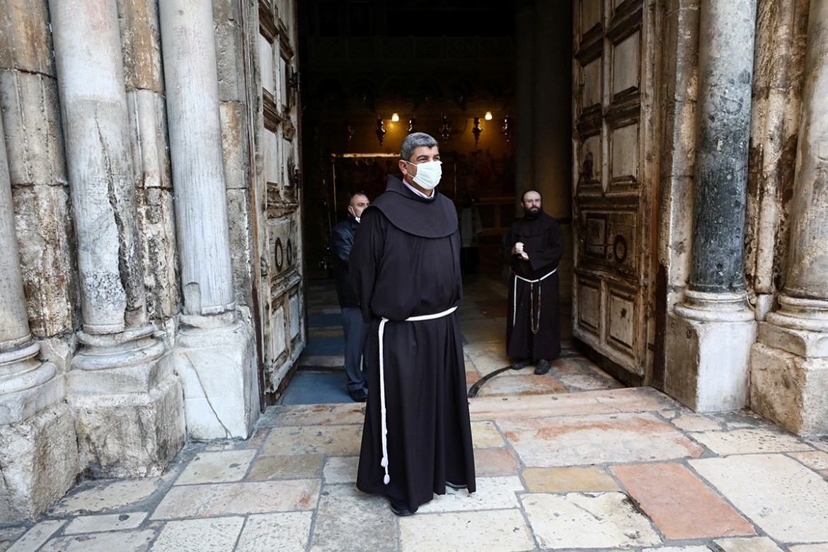 A Franciscan friar wearing a mask stands at the entrance of the Church of the Holy Sepulchre before the start of the Easter Sunday service amid the coronavirus disease (COVID-19) outbreak, in Jerusale