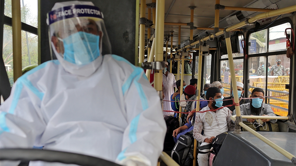 Men wearing protective masks sit inside a bus that will take them to a quarantine facility, amid concerns about the spread of coronavirus disease (COVID-19), in Nizamuddin area of New Delhi, India, Ma