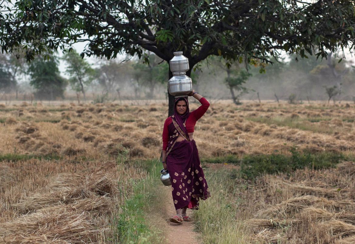 Gyanvati, a migrant worker, carries pots filled with water after she returned home from New Delhi during nationwide lockdown in India to slow the spread of the coronavirus, in Jugyai village in the ce