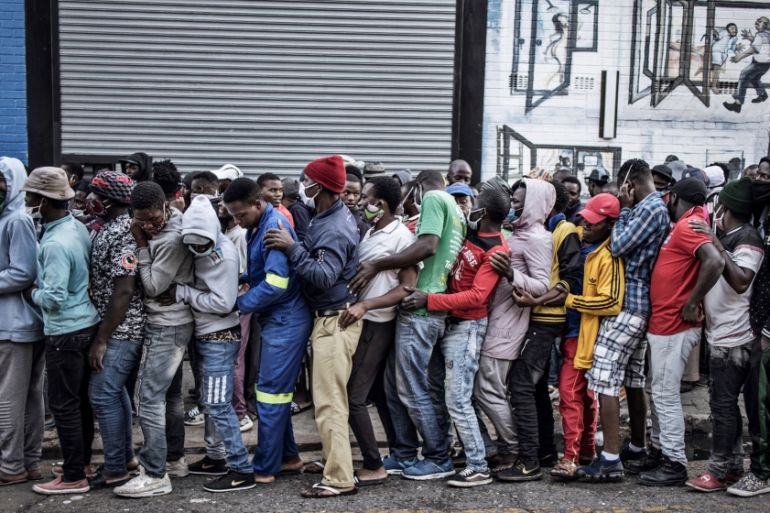 People queue to receive food during a distribution organised by the local Muslim organisation Ghous-e-aazam Welfare, in the Kwa Mai Mai area of the Johannesburg CBD, on May 5, 2020 as the country figh
