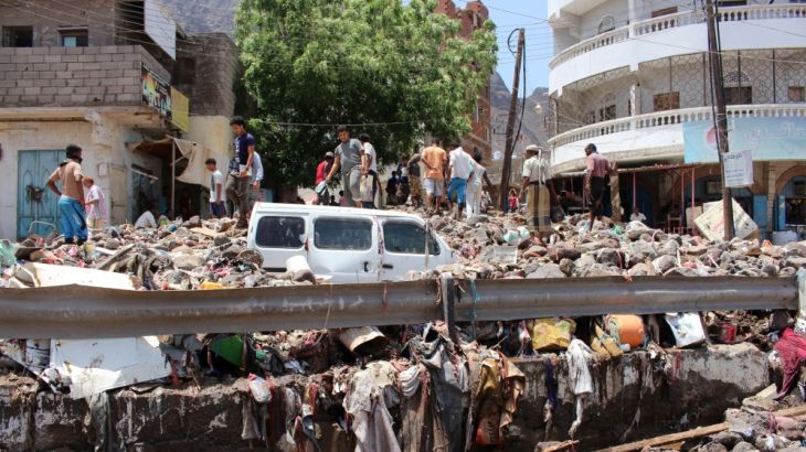 People inspect damage caused by floods on a street in Aden, Yemen