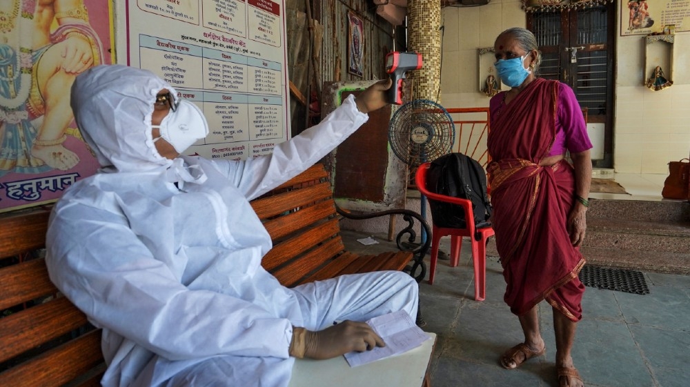 Sanjay Meriya, 30, also known as the Spindoctor, wearing a protective gear checks temperature of a woman in a temporary health center where he coaches slum dwellers on the precautions 