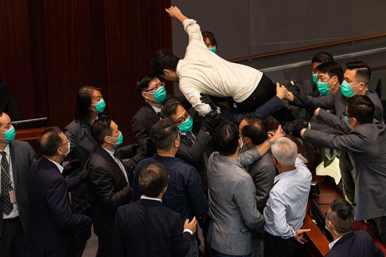 epa08428890 Pro-democracy lawmaker Ted Hui (C, top) is carried out of the chamber by security guards during a scuffle with pro-Beijing lawmakers at a the Legislative Council meeting in Hong Kong, Chin