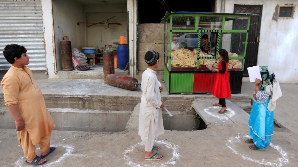 Afghan youths stand on social distancing markers as they buy bread from a bakery, amid the spread of the coronavirus disease (COVID-19), in Jalalabad, Afghanistan May 8, 2020. REUTERS/Parwiz