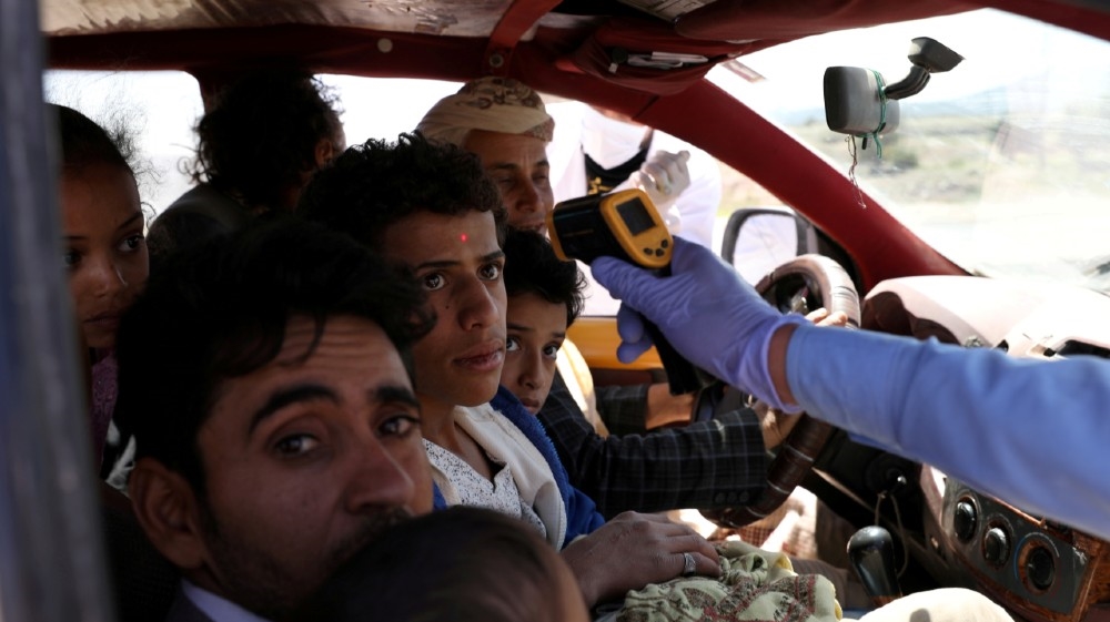 A health worker takes the temperature of people riding a taxi van, amid concerns of the spread of the coronavirus disease (COVID-19), at the main entrance of Sanaa, Yemen May 9, 2020. 
