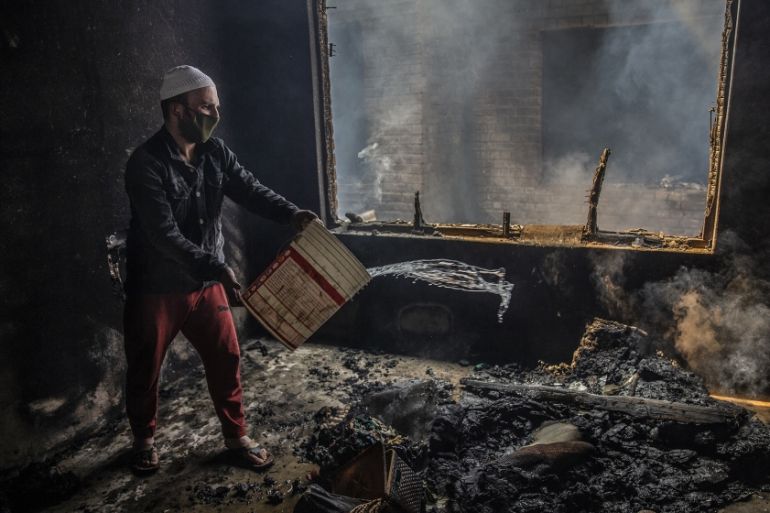 A Kashmiri man douses a fire in a house which was damaged in a gun-battle in Srinagar, Indian controlled Kashmir, Tuesday, May 19, 2020. Indian government forces killed two rebels in disputed Kashmir