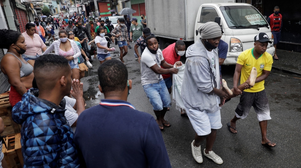 Residents carry a dead body after a police operation against drug gangs in Rio de Janeiro
