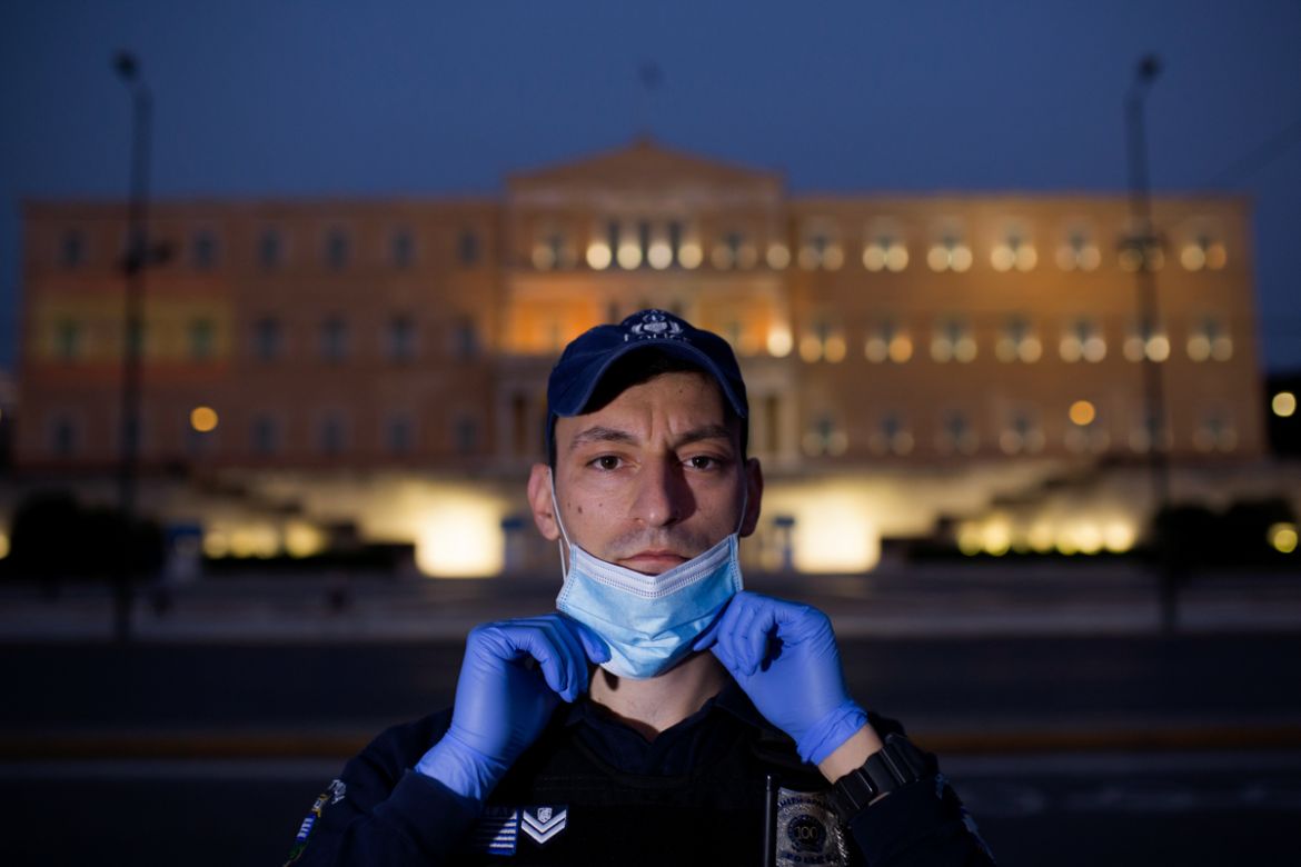epa08392756 (03/13) Police officer Stergios Kakarotzas, 28, wearing a protective face mask and gloves poses for a picture in front of the parliament building during the lockdown of the coronavirus dis