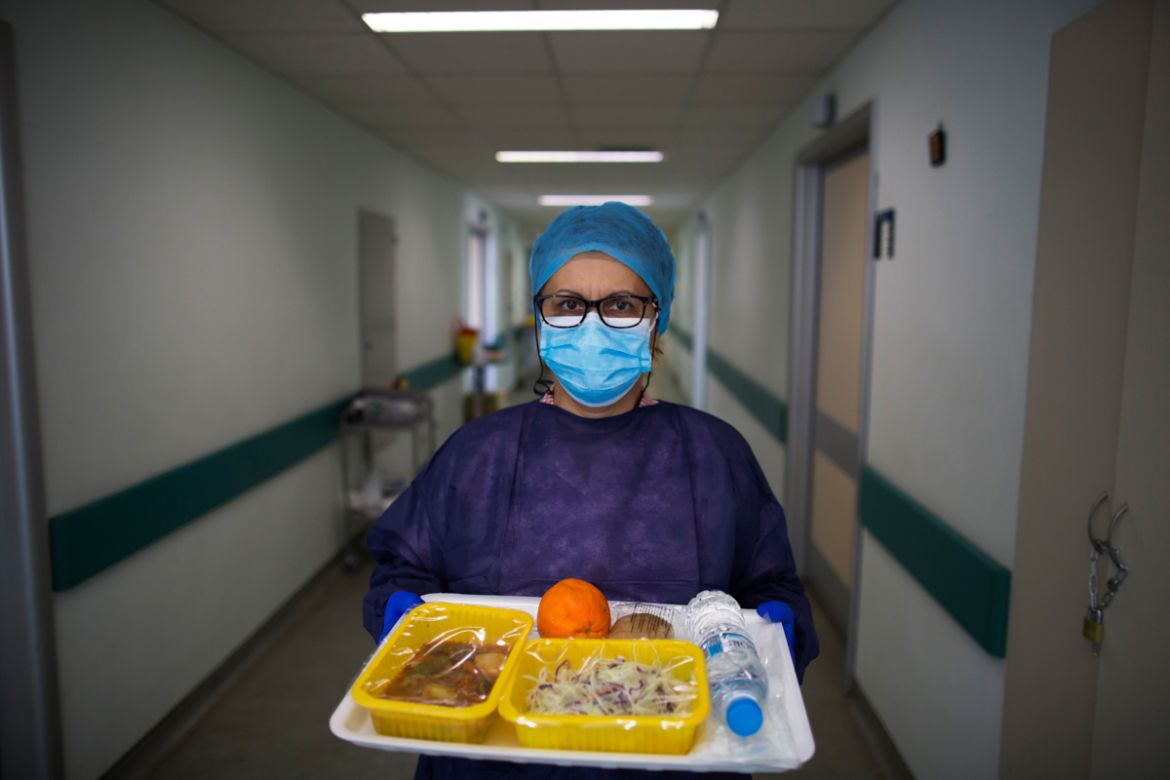 epa08392758 (05/13) Medical staff Eleni Griva, 51, wearing a protective face mask and gloves poses for a picture as she delivers lunch for patients affected by COVID-19, during the country lockdown, a