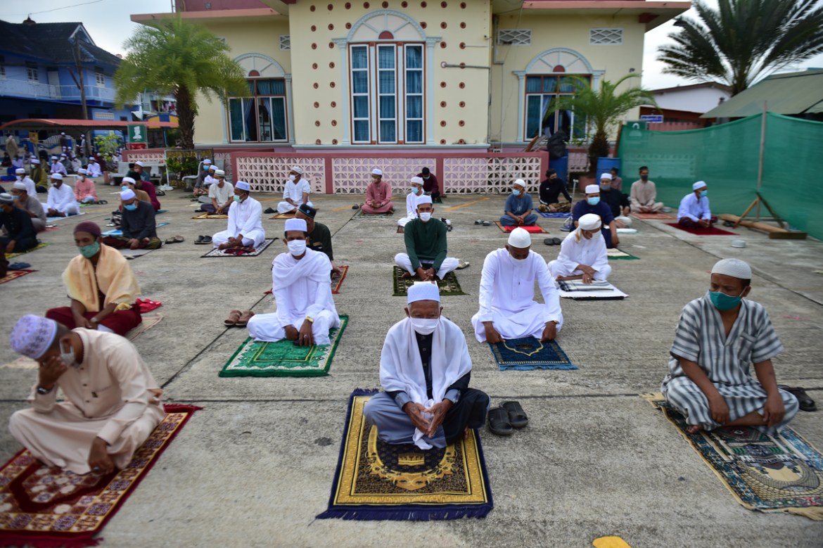 Muslim men wearing face masks and sitting apart to practice social distancing pray in the grounds of Yakaniah mosque on the first day of the Eid al-Fitr holiday which marks the end of the Muslim holy