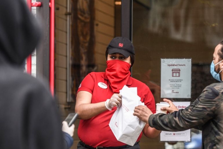 An employee wearing a protective mask and gloves hands out takeout orders to customers outside a Chick-fil-A Inc. restaurant in the Brooklyn Borough of New York, U.S., on Wednesday, April 15, 2020. Ne
