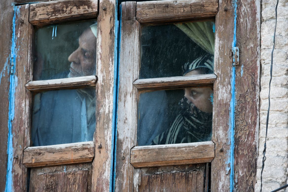 Residents watch out from their window in an area near the site of a gun battle between suspected militants and government forces in Srinagar on May 19, 2020. - Two Kashmir militants including a key re