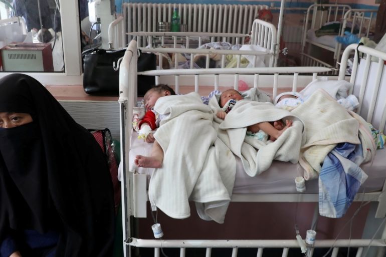 Newborn children who lost their mothers lie on a bed at a Kabul hospital