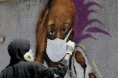 Serigne 'Zeus' Boye, a graffiti artist, works on his mural to encourage people to protect themselves amid the COVID-19 outbreak in Dakar, Senegal on March 25, 2020 [File: Zohra Bensemra/Reuters]