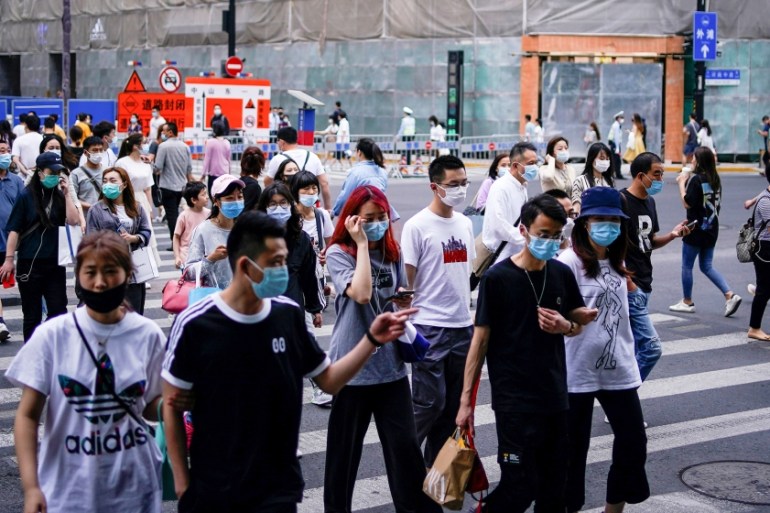 People wearing protective face masks are seen on a street following an outbreak of the novel coronavirus disease (COVID-19), in Shanghai, China May 25, 2020. REUTERS/Aly Song