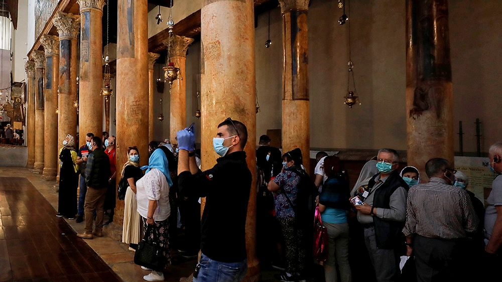A visitor wearing a mask as a preventive measure against the coronavirus takes pictures in the Church of the Nativity in Bethlehem in the Israeli-occupied West Bank March 5, 2020. REUTERS/Mussa Qawasm