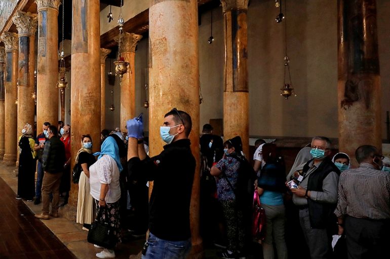 A visitor wearing a mask as a preventive measure against the coronavirus takes pictures in the Church of the Nativity in Bethlehem in the Israeli-occupied West Bank March 5, 2020. REUTERS/Mussa Qawasm