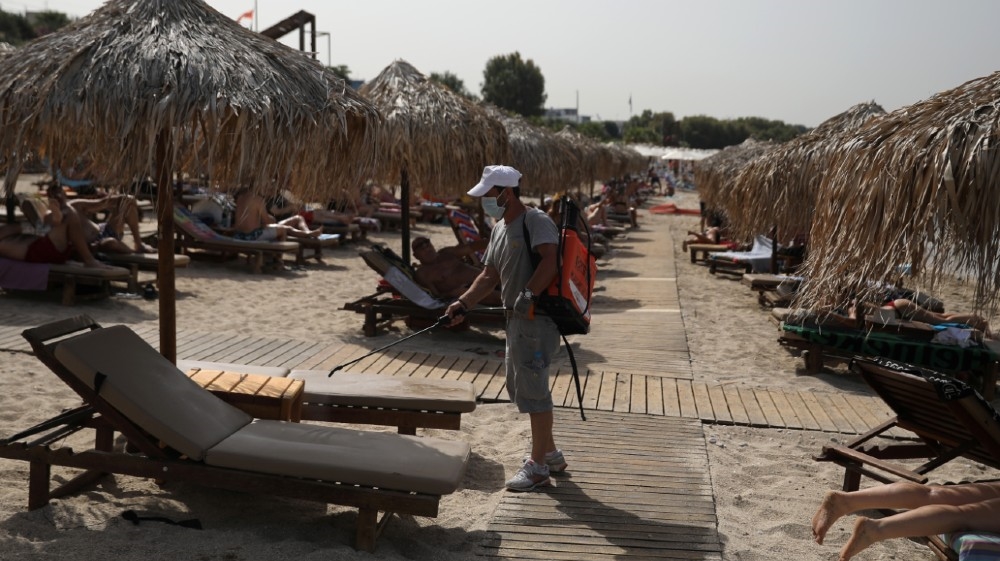 A man wearing a face mask disinfects a sunbed during the official reopening of beaches to the public following the easing of measures against the spread of the coronavirus disease (COVID-19), 
