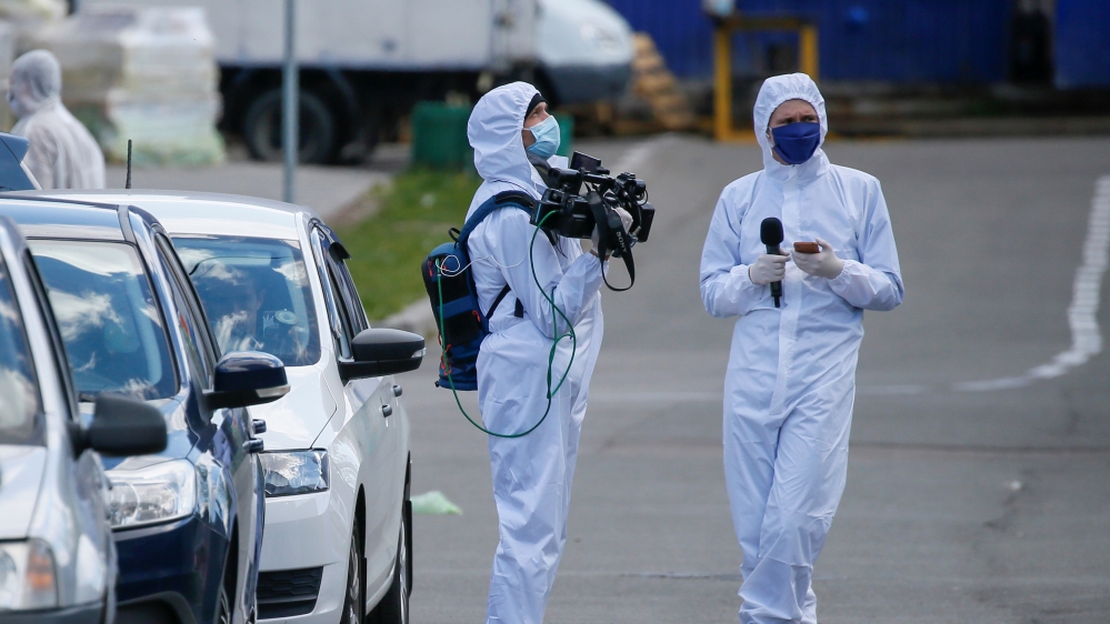 Journalists wearing protective gear wait near a quarantined hostel in Kiev