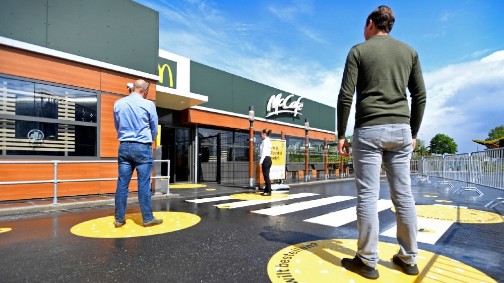 Customers wait outside on social distancing markings at a prototype location of fast food giant McDonald's for restaurants which respect the 1.5m social distancing measure, 