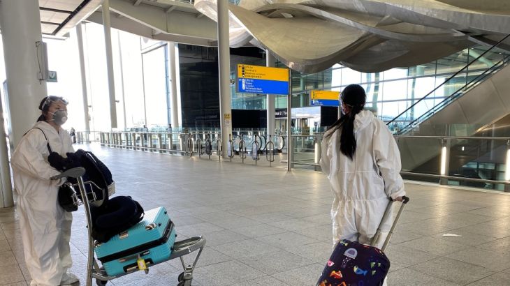 Passengers wearing protective clothing are seen at Heathrow Airport, London