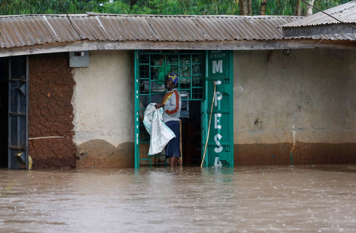 A woman stands in food waters next to a shop, after after River Nzoia burst its banks and due to the backflow from Lake Victoria ,in Buyuku village of Budalangi, in Busia County, Kenya May 2, 2020. RE