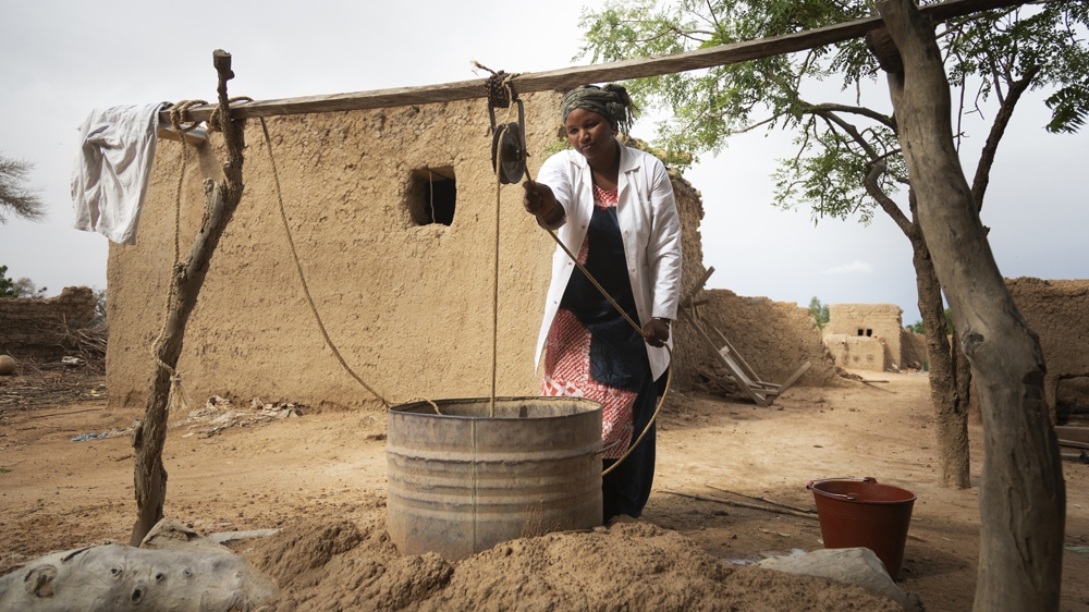 Salimata Dagnogo, 32, Matron of Talo Health Centre, collects dirty water from an open well in the village. Salimata has worked at Talo for eight years and faces big challenges in her role without the 