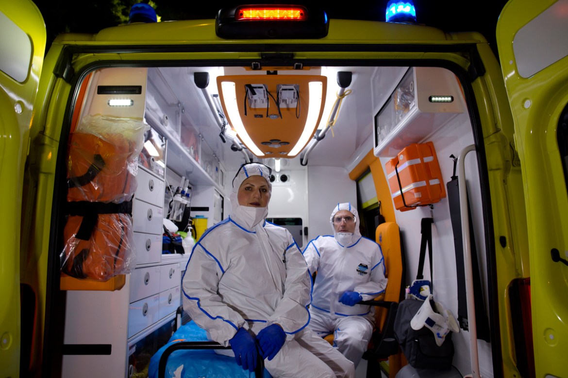 epa08392763 (10/13) Rescuers Konstantina Papachristodoulou (L), 39, and Thomas Koulakiotis (R), 48, wearing protective suits pose for a picture as they sit inside an ambulance, during the lockdown of