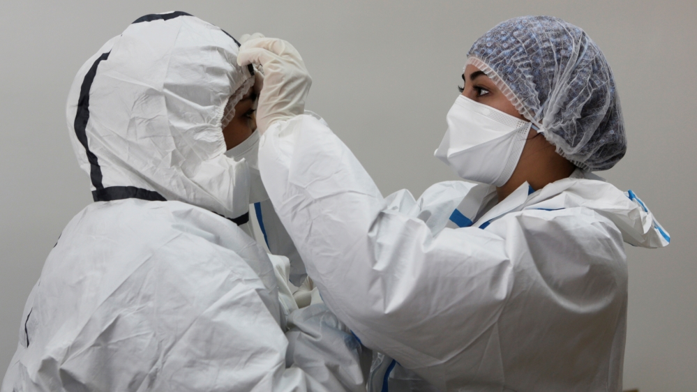 Nurse Chaimaa helps Doctor Meryem Bouchbika to adjust her protective gear in Sale