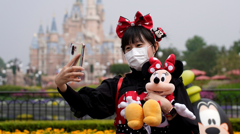 A visitor dressed as a Disney character takes a selfie while wearing a protective face mask at Shanghai Disney Resort as the Shanghai Disneyland theme park reopens following a shutdown due to the coro