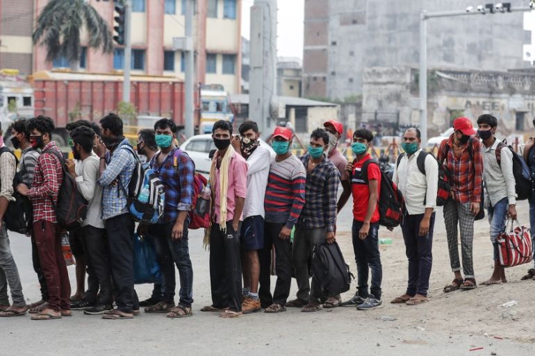 Migrant workers who arrived from neighboring Maharashtra state line up to board a truck as they are transported to a quarantine center in Prayagraj, Uttar Pradesh state, India, Sunday, May 10, 2020. I