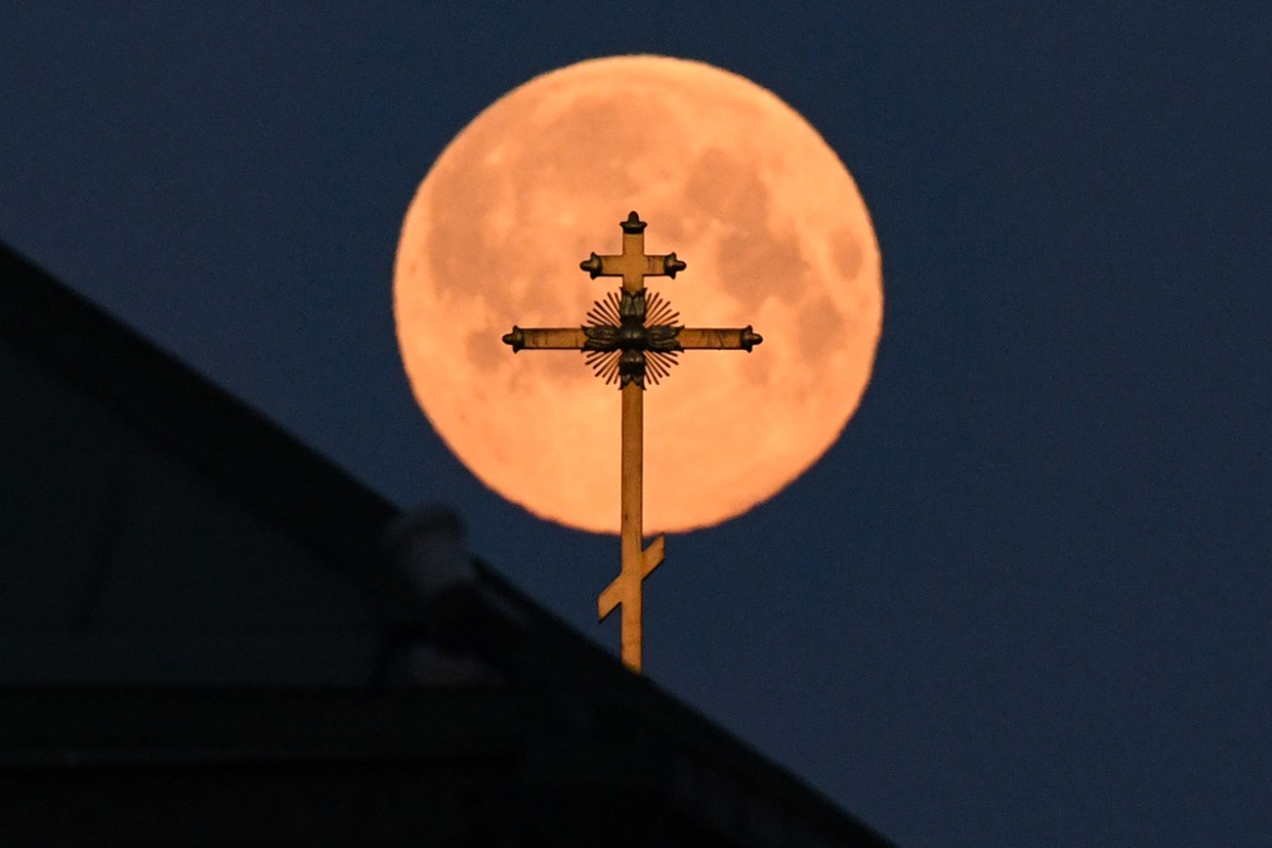 This picture taken early on April 8, 2020 shows the closest supermoon to the Earth, also known as a pink moon, behind the cross on a church in downtown Moscow. Kirill KUDRYAVTSEV / AFP