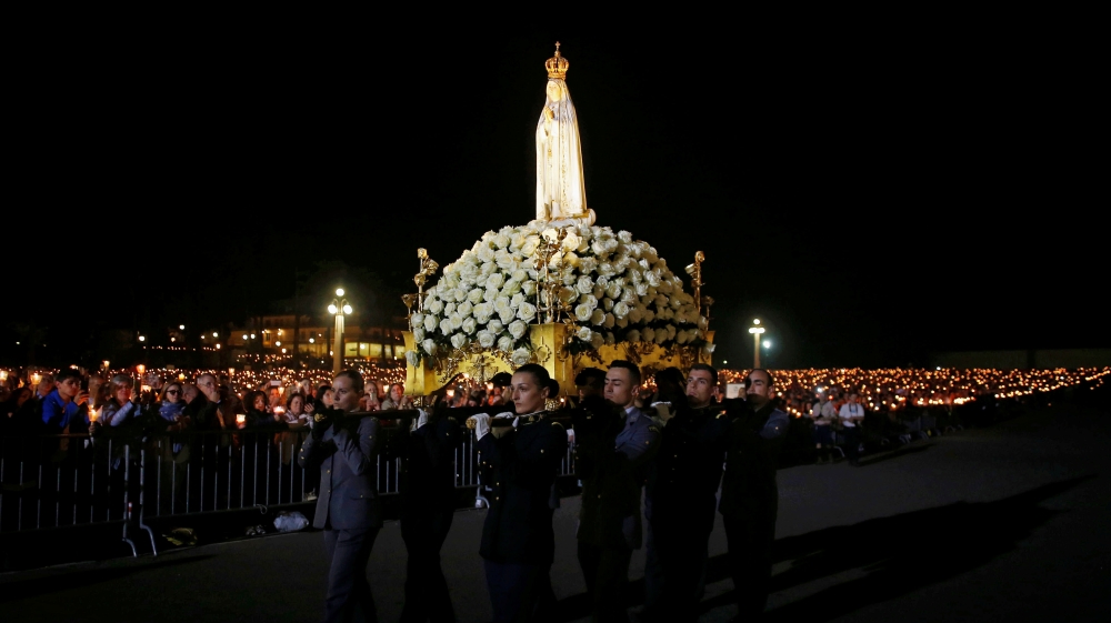 People carry the statue of Our Lady of Fatima during the 102nd anniversary of the appearance of the Virgin Mary to three shepherd children at the Catholic shrine of Fatima