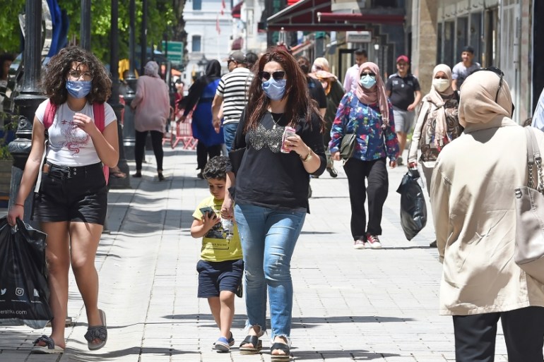 Tunisian people wearing protective face masks walk in the Habib Bourguiba avenue in the Tunisian capital Tunis on May 12, 2020, following the easing of the lockdown measures put in place to combat the