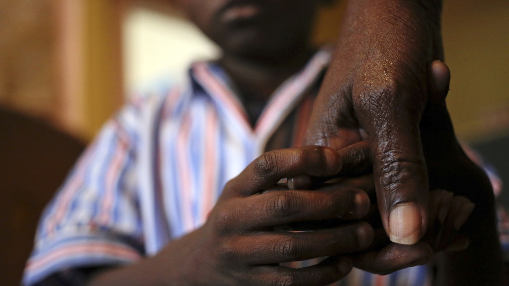 Nine-year-old Tumelo holds his grandmother's hand after taking his medication at Nkosi's Haven, south of Johannesburg