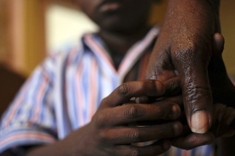 Nine-year-old Tumelo holds his grandmother''s hand after taking his medication at Nkosi''s Haven, south of Johannesburg