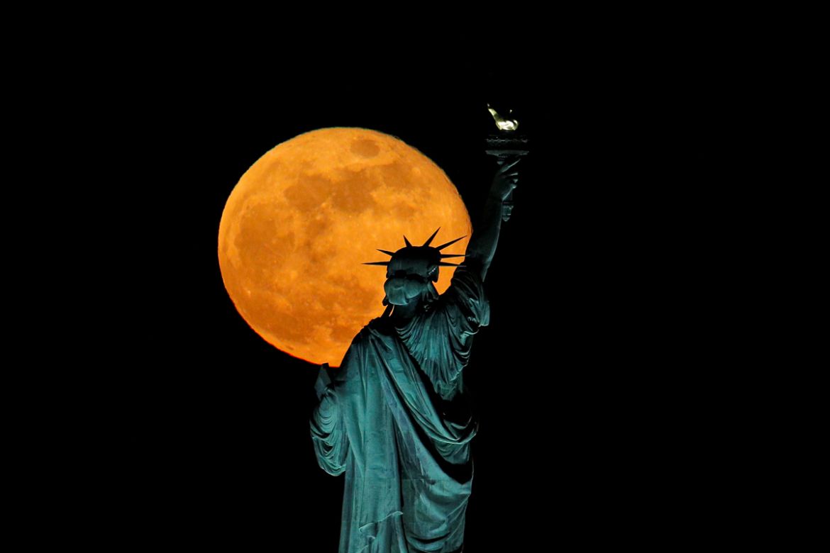 The full moon, also known as the Supermoon or Flower Moon, rises above the Statue of Liberty, as seen from Jersey City, New Jersey, U.S., May 7, 2020. REUTERS/Brendan McDermid TPX IMAGES OF THE DAY