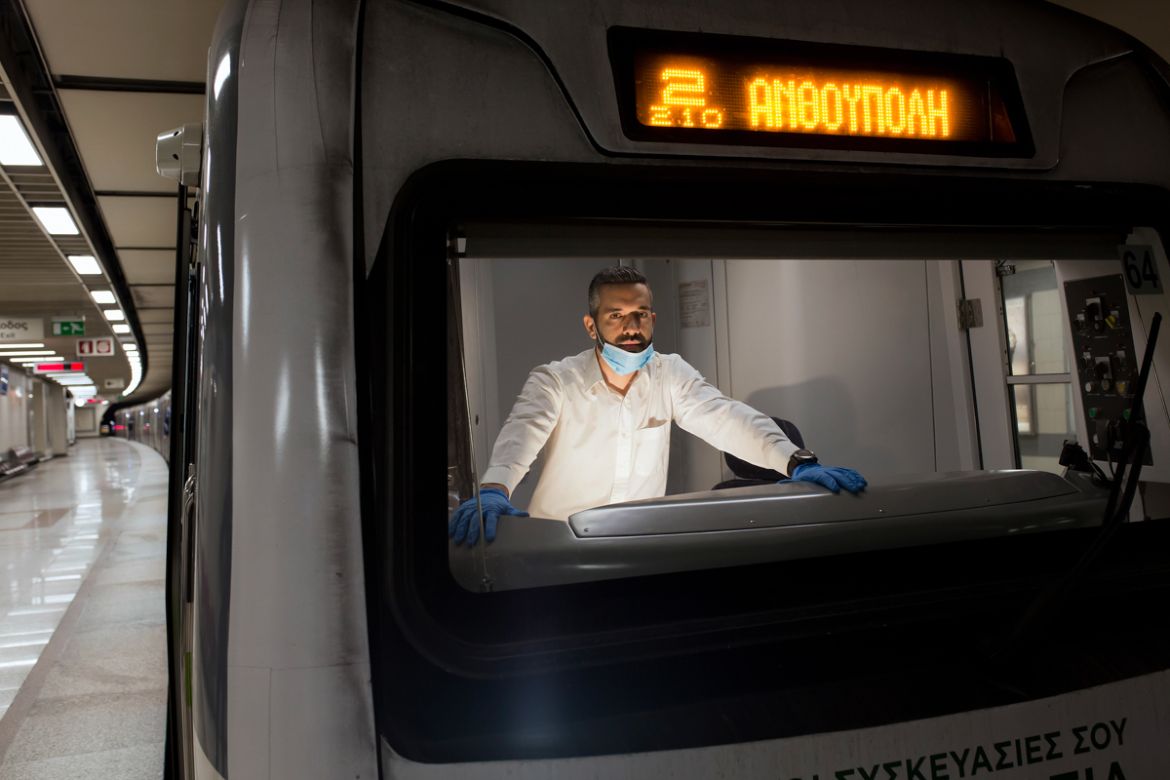 epa08392754 (01/13) Metro train driver Alexandros Barbounis, 36, wearing a protective face mask and gloves poses for a picture inside the train cockpit, during the lockdown of the coronavirus disease