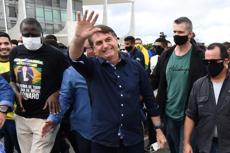 Brazil''s President Jair Bolsonaro greets supporters upon arrival at Planalto Palace in Brasilia, on May 24, 2020, amid the COVID-19 coronavirus pandemic. Despite positive signs elsewhere, the disease