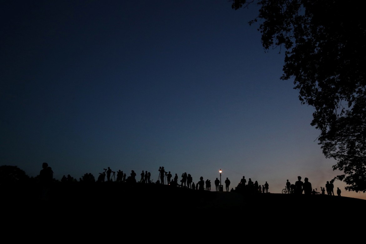 Silhouettes of media members and people document the full moon, also known as the Supermoon or Flower Moon, over Primrose Hill, London, Britain, May 7, 2020. REUTERS/Hannah McKay