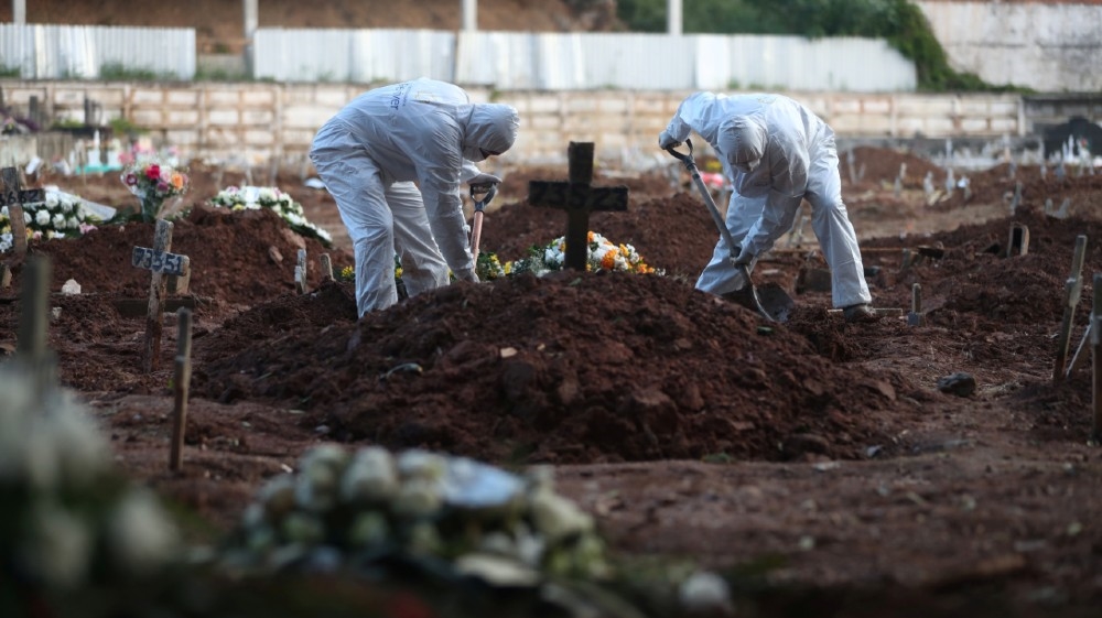 Gravediggers wearing protective garments work as relatives of Neide Rodrigues, 71, who died of the coronavirus disease (COVID-19), attend her burial at a cemetery in 