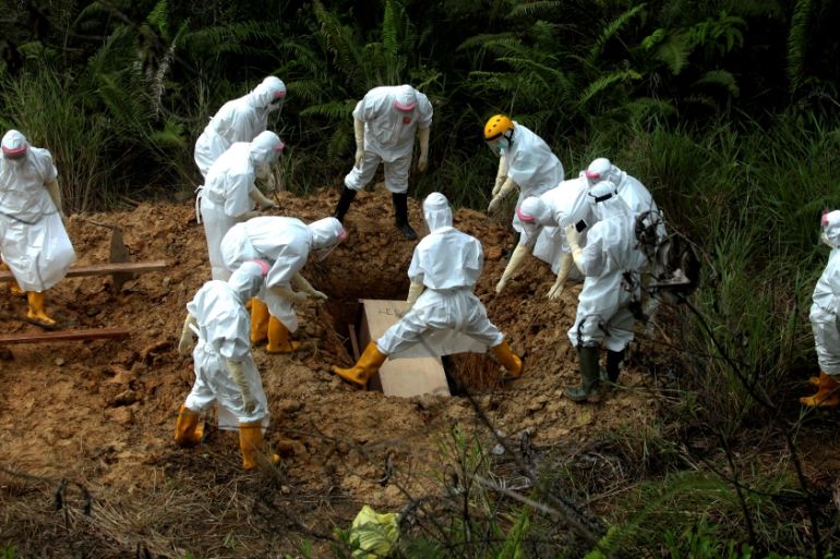 Municipality workers wearing protective gear bury a victim of the coronavirus disease (COVID-19) at a cemetery area provided by the government