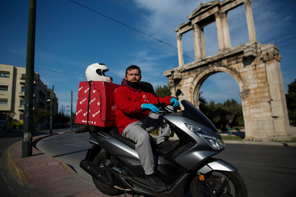 epa08392762 (09/13) Delivery company employee Andreas Porfyris, 25, wearing a protective face mask and gloves poses for a picture at the empty road in front of the ancient monument of Hadrian''s Arch,