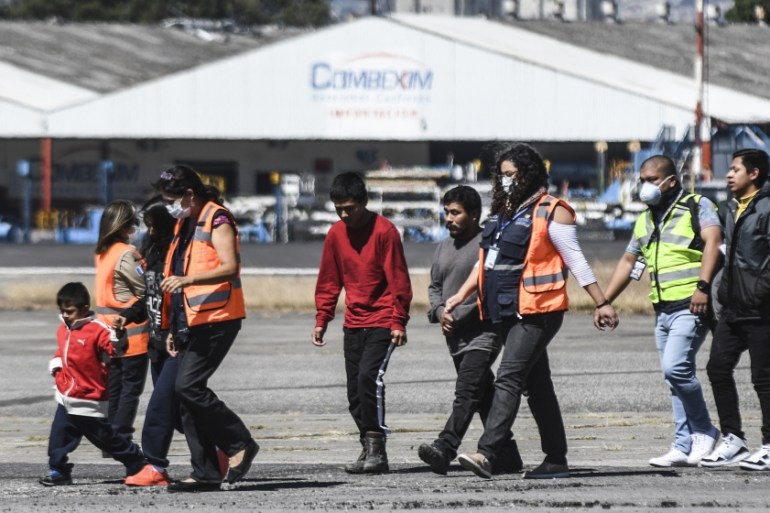 Guatemalan immigration officials use protective equipment as a preventive measure against the new coronavirus, COVID-19, as they receiving Guatemalan migrants deported from the United States, at the A