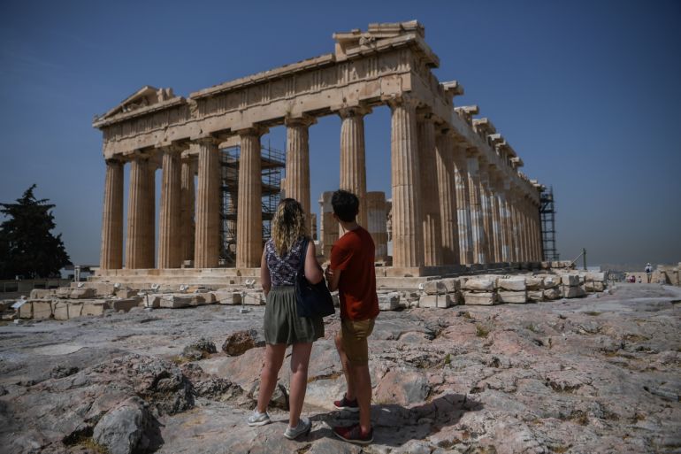 A couple visit the Parthenon temple on the archeological site of the Acropolis in Athens on May 18, 2020 amid the pandemic of the novel coronavirus (COVID-19). - Greece reopened the Acropolis in Athen
