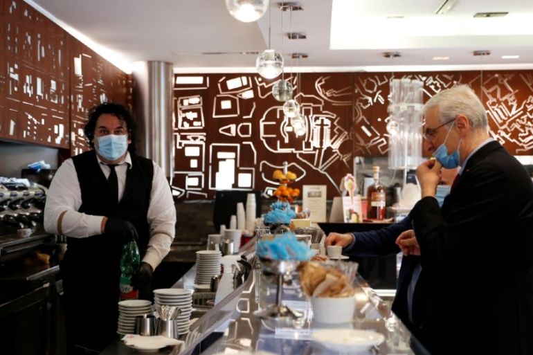 A man wearing a face mask serves a customer, as shops are allowed to reopen as Italy eases some of the lockdown measures put in place during the coronavirus disease (COVID-19)
